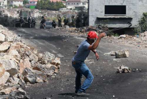 A Palestinian protestor throws stones at Israeli soldiers during a protest against the expanding of Jewish settlements in the West Bank 