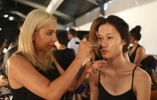 Chinese model Zhang Huijun (R) has make-up applied backstage during the 2015 New York Fashion Week in New York, the United States