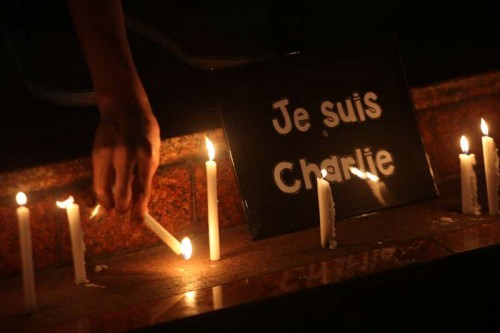  A member of the National Union of Journalists of the Philippines (NUJP) lights candles in front of a placard that reads "je suis Charlie" (I am Charlie) during a candle lighting ceremony in Quezon City, the Philippines, Jan. 9, 2015. The NUJP denounced the attack on French satirical magazine Charlie Hebdo which killed 12 people and wounded 11 others. 