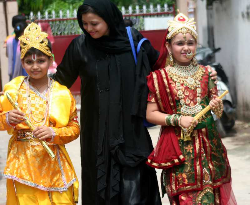 A muslim woman with her kids dressed as Lord Krishna and Radha returning home after a school competition on the eve of Janmastami in Varanasi on Aug. 16, 2014. (Photo: IANS)