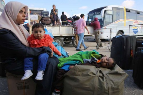 A Palestinian woman holds her boy as she waits for a travel permit to cross into Egypt, at the Rafah border crossing between Egypt and the southern Gaza Strip, June 13, 2015. Egyptian authorities opened the Rafah border crossing on Saturday for three days, in both directions to allow entry and exit of Gazan patients and students, for the first time since March 11, Palestinian officials said. 