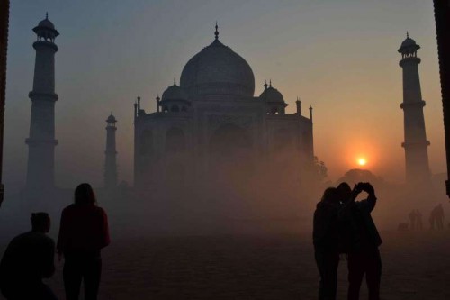 A spectacular view of Taj Mahal with a thin blanket of fog around it during the sunrise in Agra.