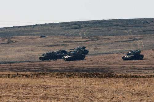 Turkish army tanks take position on the Turkish side of the Turkish-Syrian border . The Turkish security forces have taken strict security measures along the Turkish-Syrian borderline to prevent infiltrations from Syria into Turkey's territory.