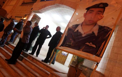 People stand by a poster of the Jordanian pilot Moaz al-Kasasbeh after the release of a video purportedly showing Islamic State captive Jordanian pilot being burnt alive in the pilot's hometown Karak, Jordan, on Feb. 3, 2015. Jordanian government on Tuesday confirmed the killing of Jordanian pilot held captive by the Islamic State (IS), 