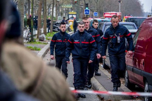  Security guards walk past the office of Charlie Hebdo in Paris, France, Jan. 7, 2015. The office of Paris Prosecutor of the Republic confirmed at least 12 people were killed on Wednesday in a shooting at the Paris office of Charlie Hebdo, a satirical newspaper, adding four others were seriously wounded in the "terror attack." 