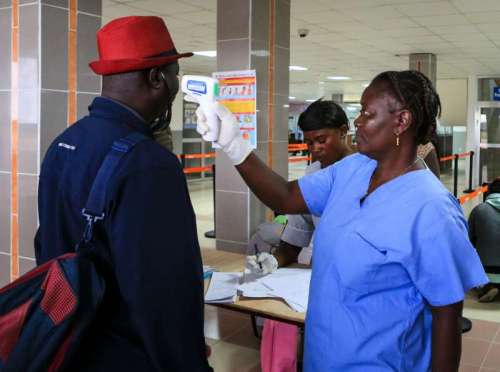 An airport worker measures body temperature for passengers at the Lungi International Airport in Freetown, capital of Sierra Leone.