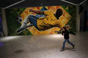 A boy runs in front of a football-themed mural inside the Brasilia International Airport in Brasilia