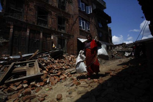 A woman collects her belongings from houses damaged by earthquake in Bhaktapur, Nepal, April 27, 2015. Death toll climbed to 3,815 following a massive 7.9-magnitude earthquake in Nepal Saturday, while 7,046 sustained injuries, says the country's ministry of foreign affairs 