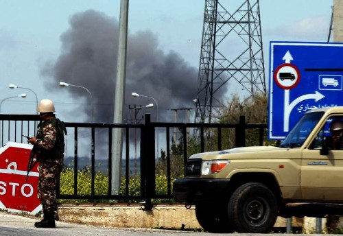  A member of the Jordanian security forces stands guard at the Jaber border crossing (known in Syria as the Nasib border) as smoke rises from the Syrian side of the border after clashes broke out near the frontier