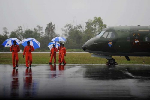 Indonesian air force pilots hold umbrellas during heavy rain while their plane is canceled to fly at Pangkalan Bun, Indonesia, Jan. 4, 2015. The search and rescue team has yet to find the black boxes of crashed AirAsia flight QZ8501 as bad weather still lingers in the crash site, an Indonesian official said