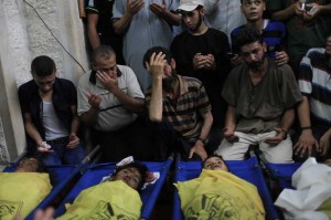  Palestinians gather around the bodies of the boys of Baker family, at a mosque before their funeral in Gaza City, on July 16, 2014. A new Israeli war jets airstrike on western Gaza city killed on Wednesday four Palestinian children and wounded ten others while they were on the beach of Gaza, medics and witnesses said. 