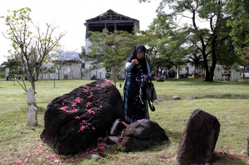  An Indonesian Muslim woman sow flowers during the commemoration of 10th anniversary of the devastating tsunami at Ulee Lheue mass grave in Banda Aceh, Indonesia, Dec. 26, 2014. A ceremony marking the devastating tsunami that hit Indonesia the worst ten years ago was held here on Friday, featuring appreciation to donor countries participating in rebuilding and rehabilitating Aceh to what it is today.