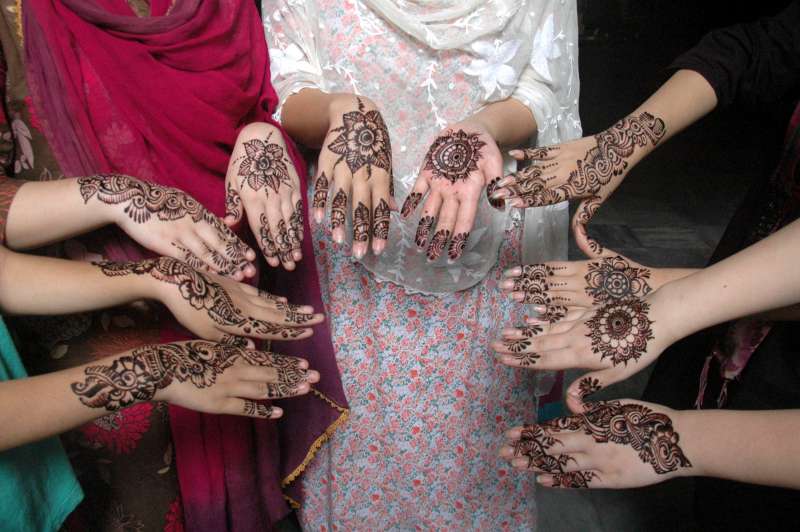 Pakistani girls show their hands painted with henna 