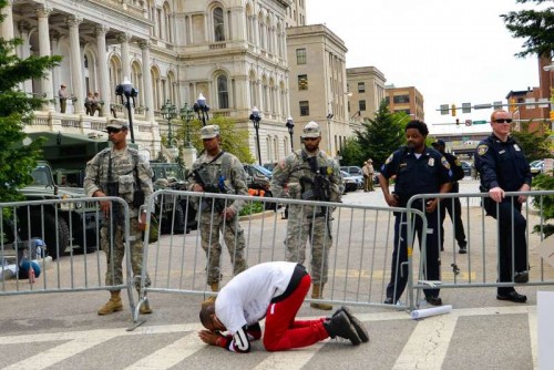 A man gets down on his knees in front of curfew zone of the City Hall in Baltimore, Maryland, the United States, May 2, 2015. Thousands of people in Baltimore, the largest city in U.S. State of Maryland, on Saturday gathered at a rally and marched through streets to celebrate a decision by the city's top prosecutor to charge six officers in connection with the death of Freddie Gray, the young African-American man who died in police custody from a spinal injury. 