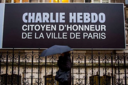 A pedestrian walks past an advertisement of Charlie Hebdo in Paris, France, on Jan. 9, 2015. Paris on Friday made the satirical magazine Charlie Hebdo an "honorary citizen" as part of support to the weekly which lost its main cartoonists in a deadly shooting on Wednesday. 