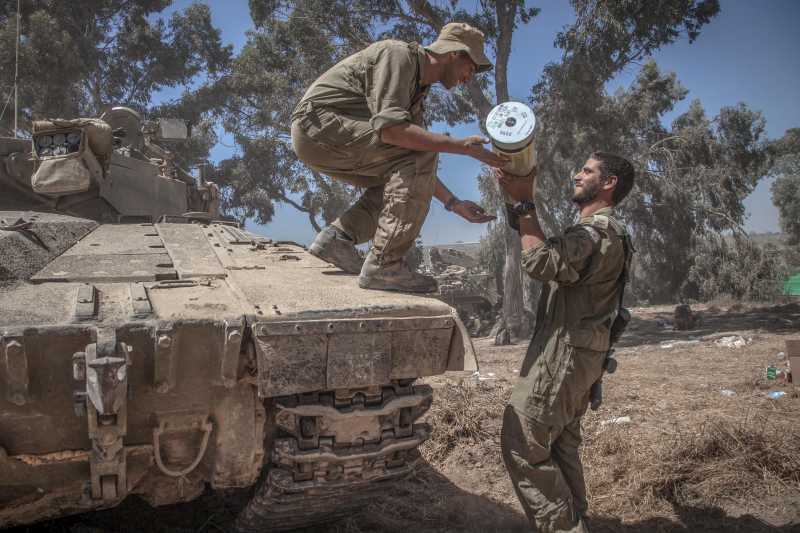  An Israeli soldier hands a shell to another on a Merkava tank at an army deployment area in southern Israel near the border with Gaza