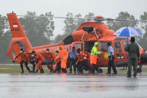 Search and Rescue (SAR) team members move a body bag containing the seventh victim of AirAsia flight QZ8501 from a helicopter at Iskandar Air Base in Pangkalan Bun, Central Kalimantan, Indonesia, Jan. 1, 2015. After battling with bad weather, searchers have so far found seven bodies of victims of AirAsia flight QZ8501, officials said Wednesday.?