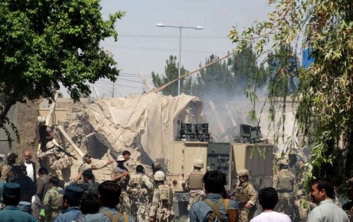 Afghan policemen gather around a building which was occupied by Taliban militants at the site of an attack in Helmand province in southern Afghanistan on May 13, 2015. Some seven people were killed while seven others were wounded in a shooting in Lashkar Gah, the capital city of southern Afghanistan's province of Helmand