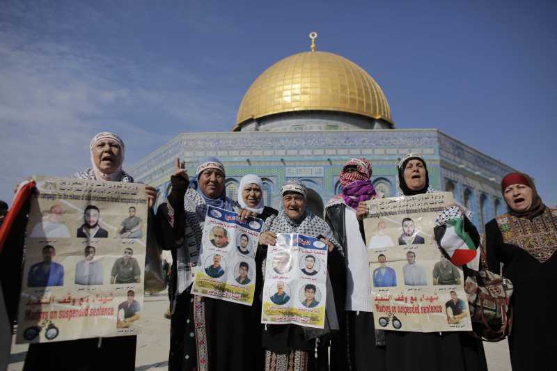 Palestinian protesters shout slogans and hold portraits of relatives incarcerated in Israeli jails during a demonstration in solidarity with Palestinian prisoners outside Jerusalem's Dome of the Rock mosque at the Al-Aqsa mosque's compound, in Jerusalem's old city, 