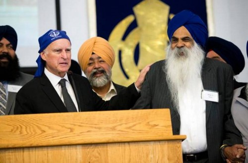 California Governor Jerry Brown holds a kirpan, a ceremonial sword carried by baptized Sikhs, given to him by Didar S. Bains, right center, during a ceremony Sunday honoring Bains at the Sikh temple in West Sacramento. Photo Credit: The Sacramento Bee