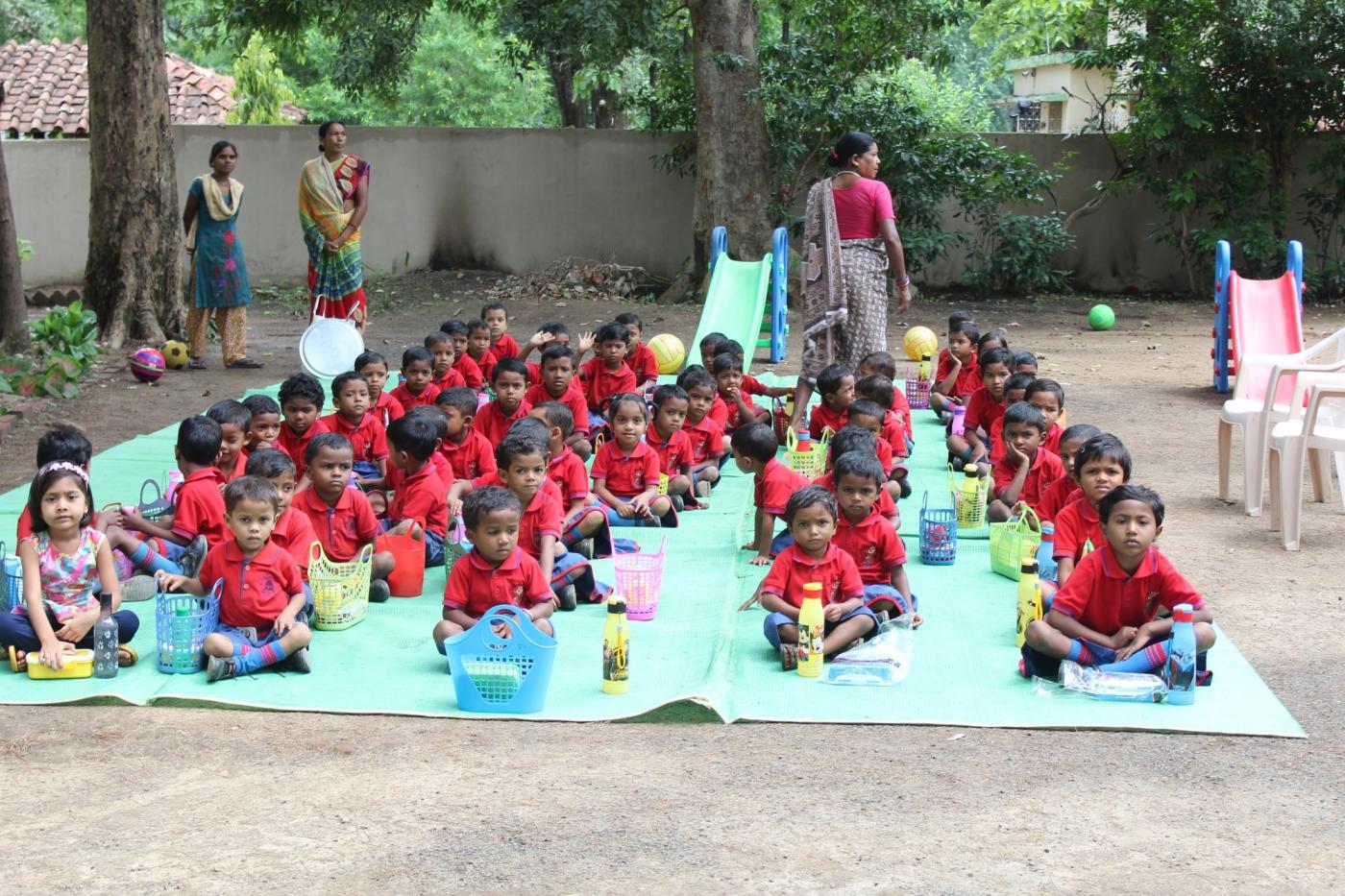 Students dressed in their red school uniforms assemble in the lawn for nutritious meals provided by the school. by . 