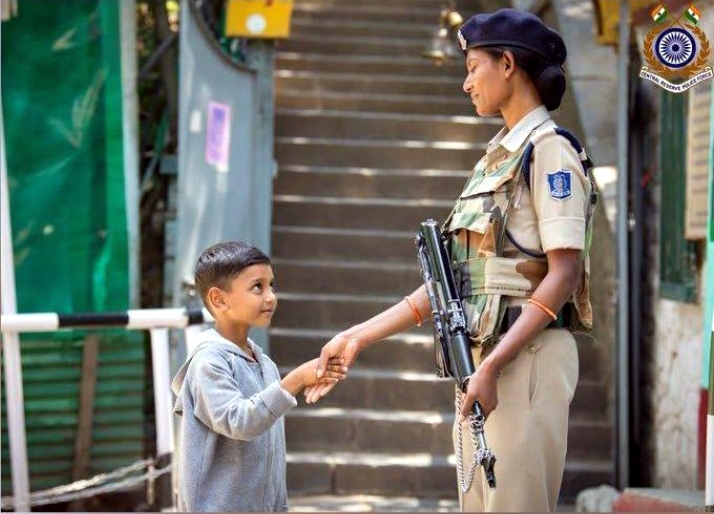 Woman CRPF personal shaking hands with kid in Kashmir. by . 